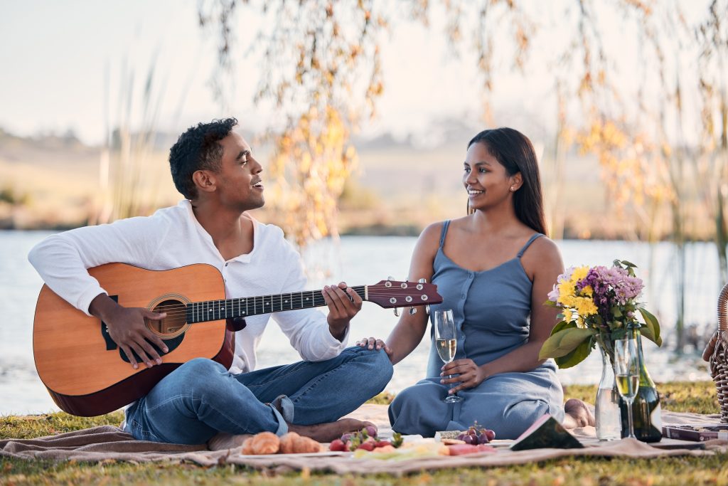 Mann spielt mit Gitarre während Frau zuhört
